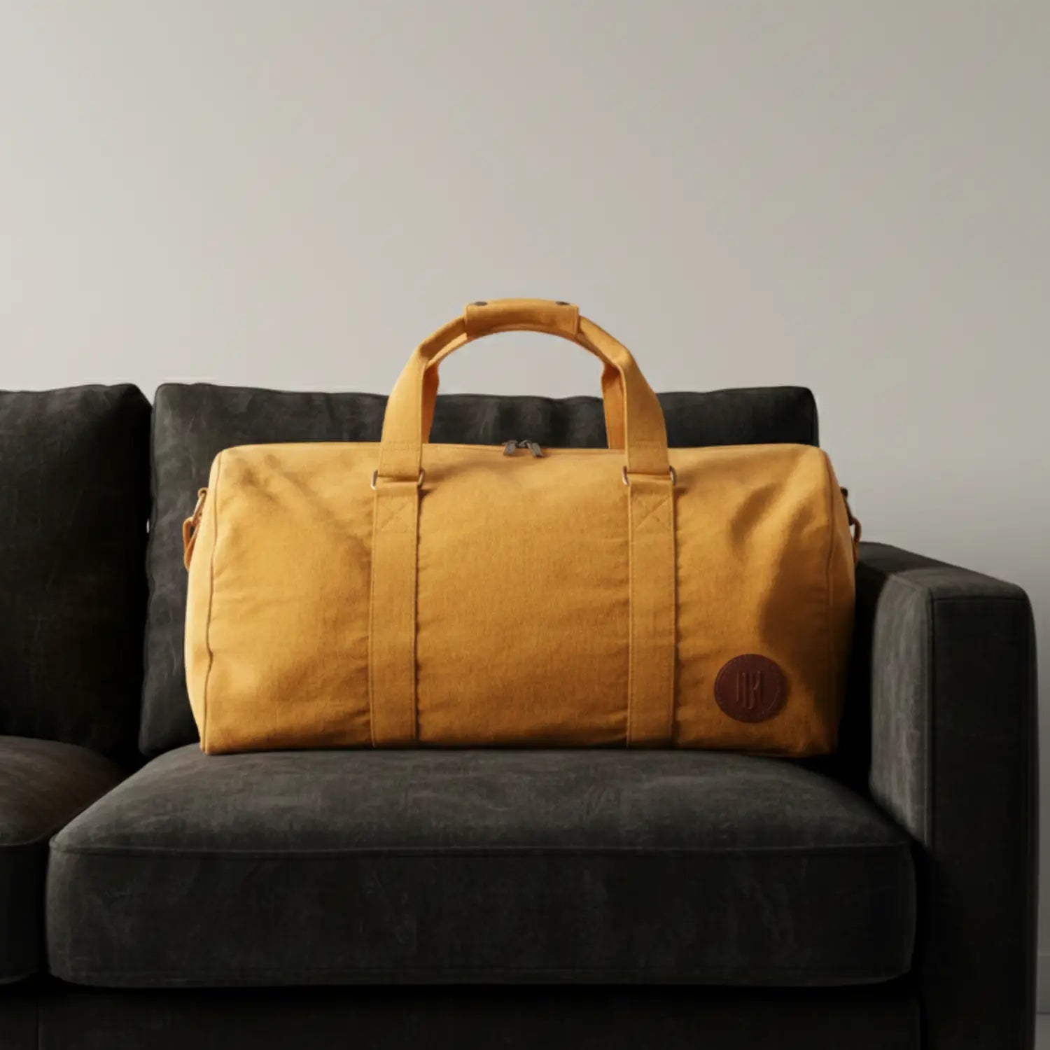 Mustard Yellow duffel bag on a dark gray couch against a plain background