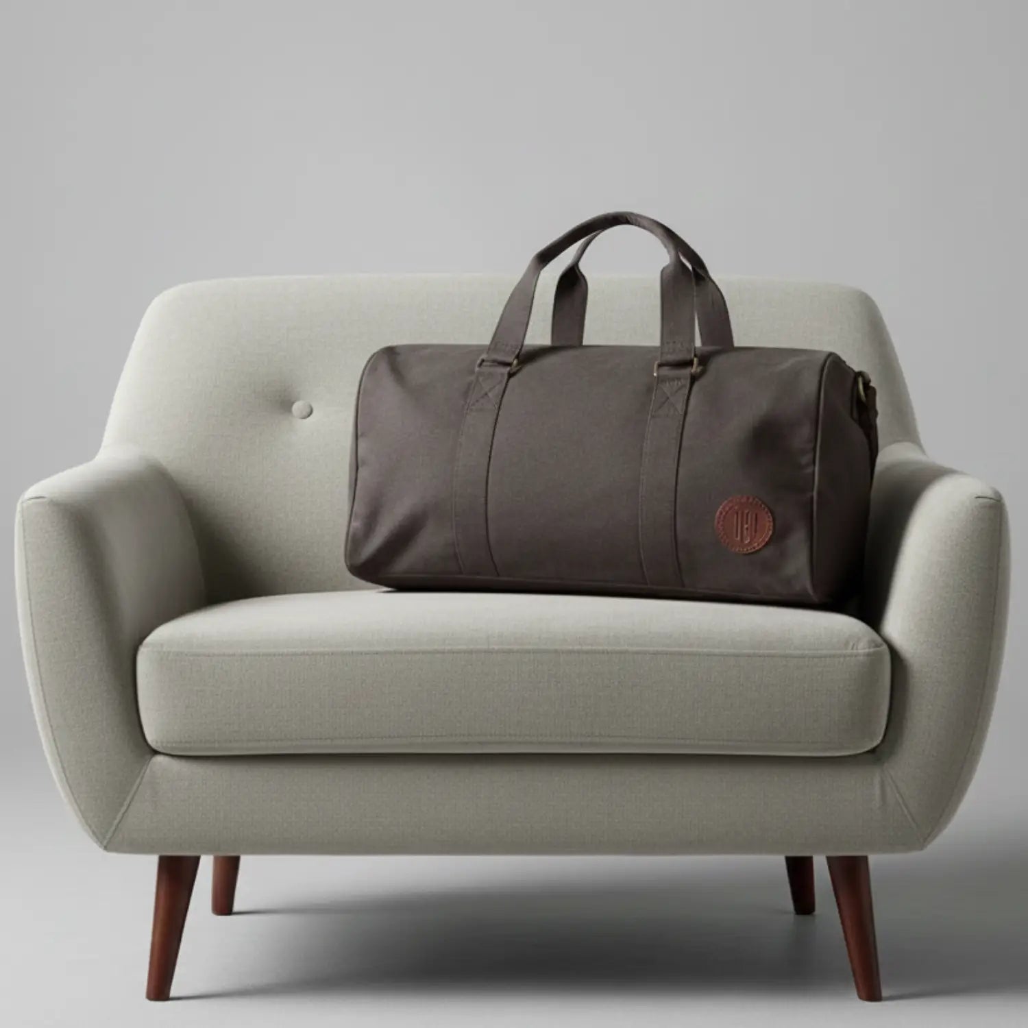 Brown duffel bag on a light gray sofa against a plain background