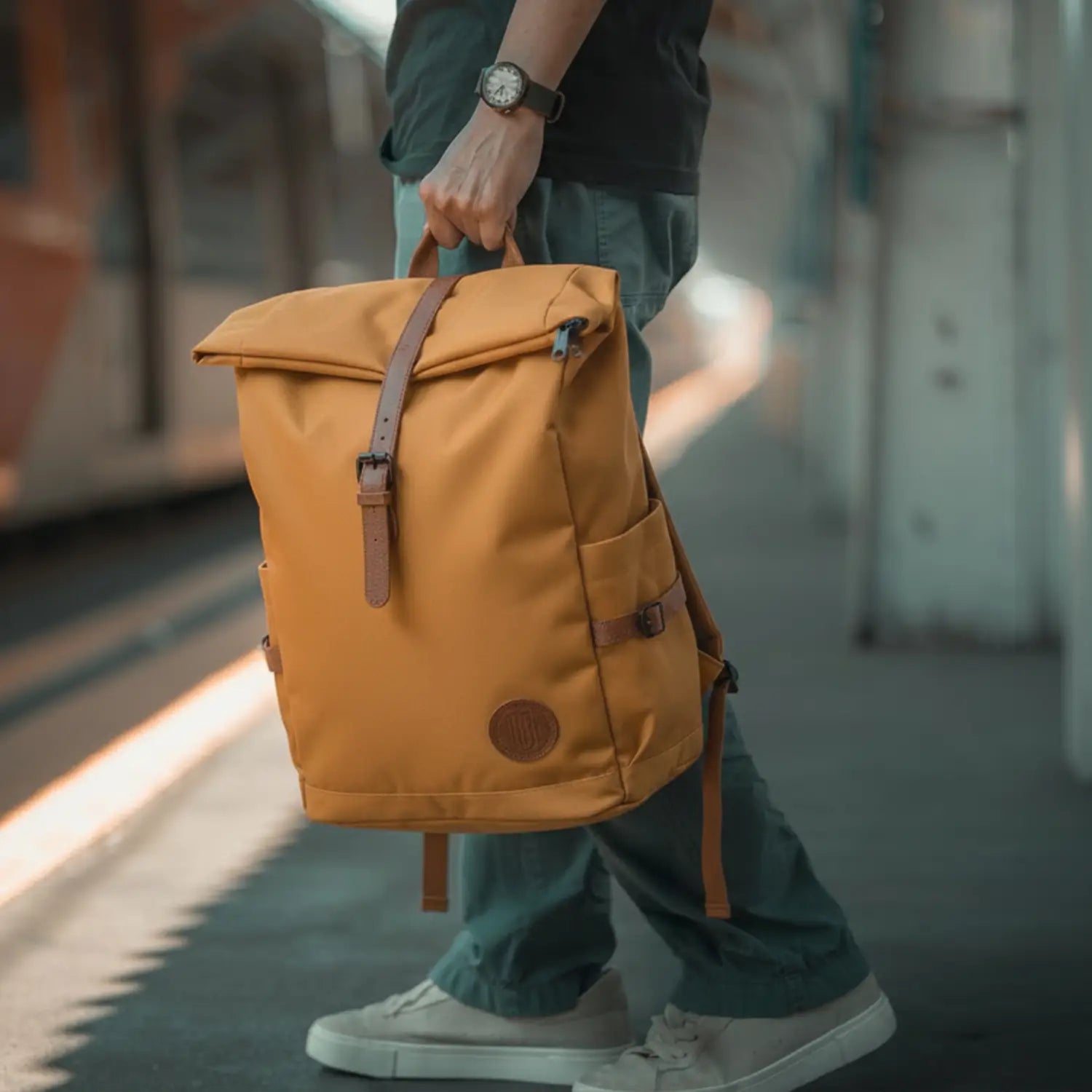 Person holding a mustard yellow backpack in an urban setting