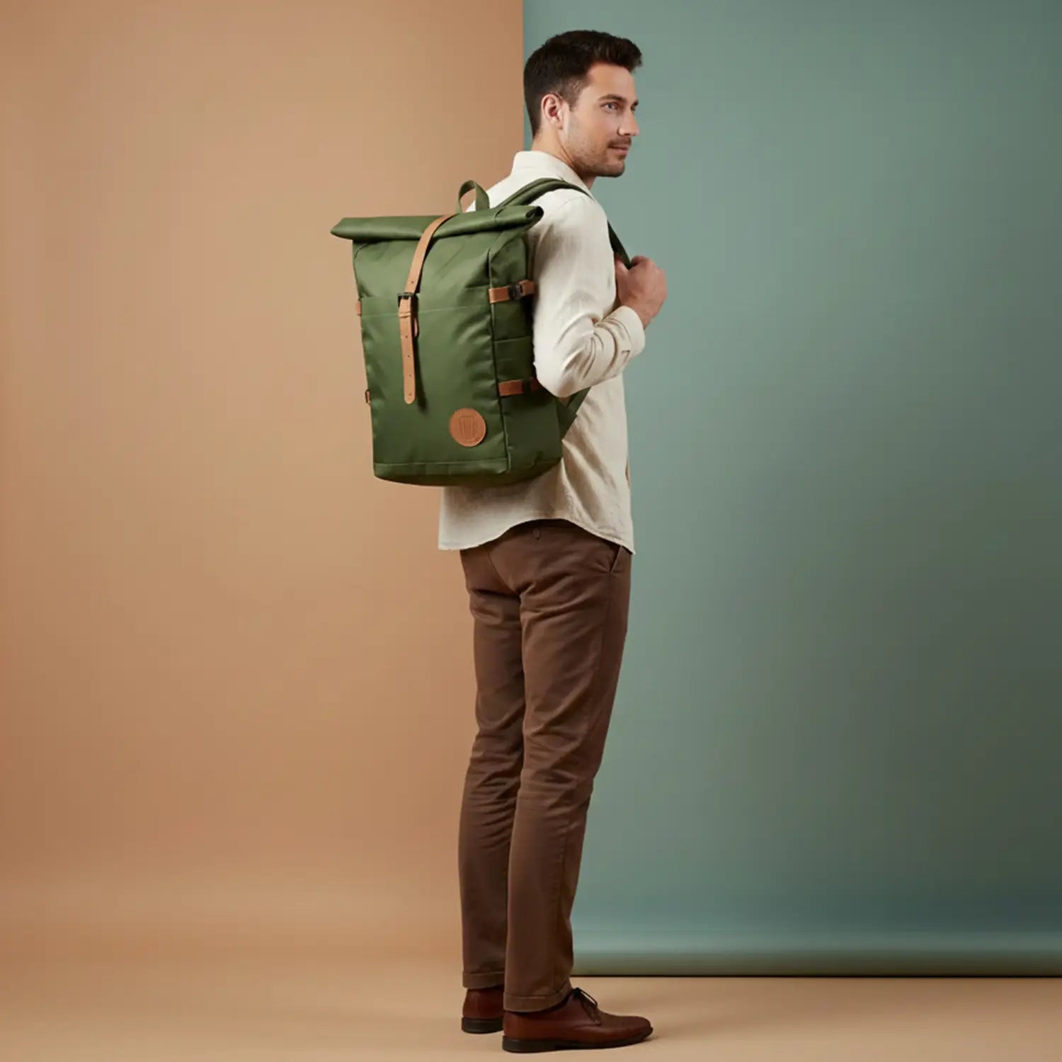 Man wearing a green backpack against a two-tone wall.