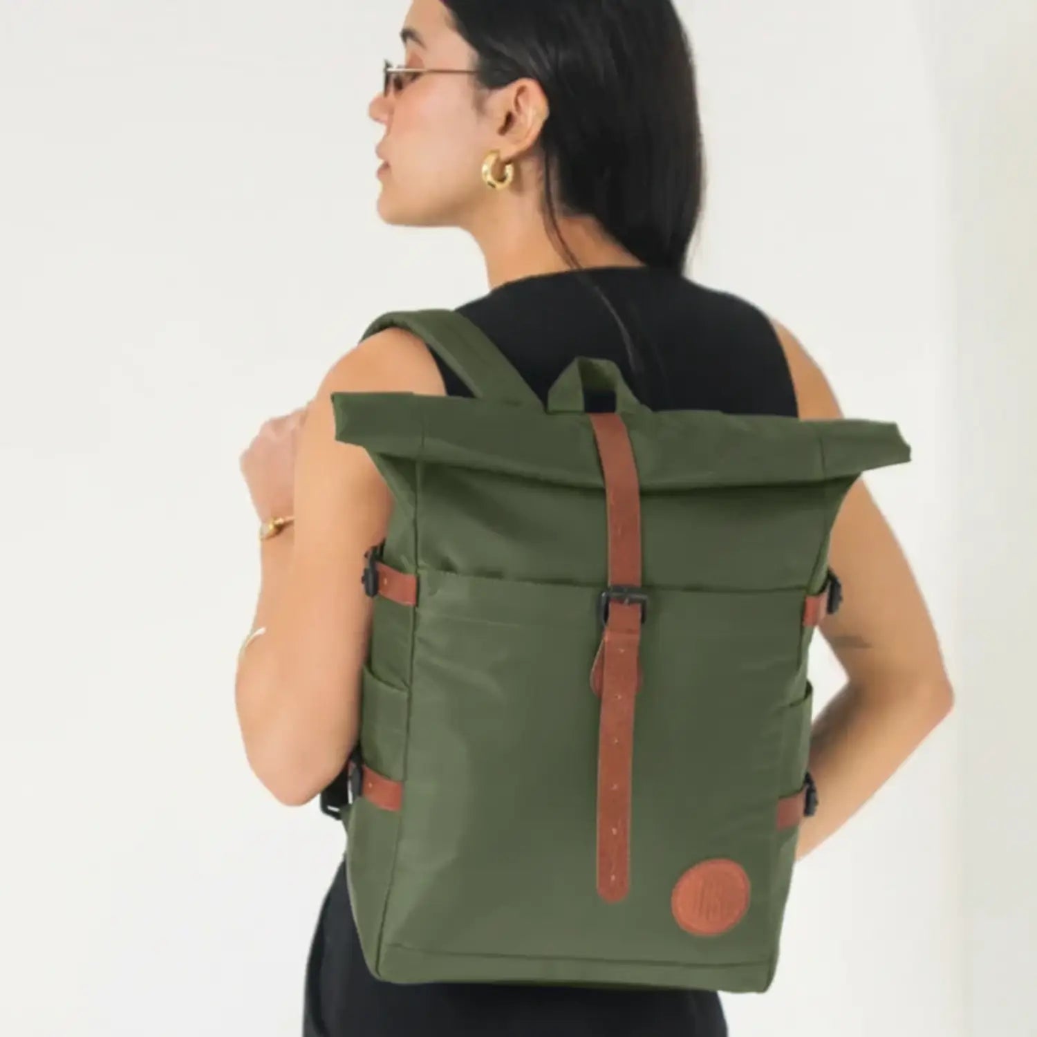 Person wearing a green backpack with brown straps on a white background
