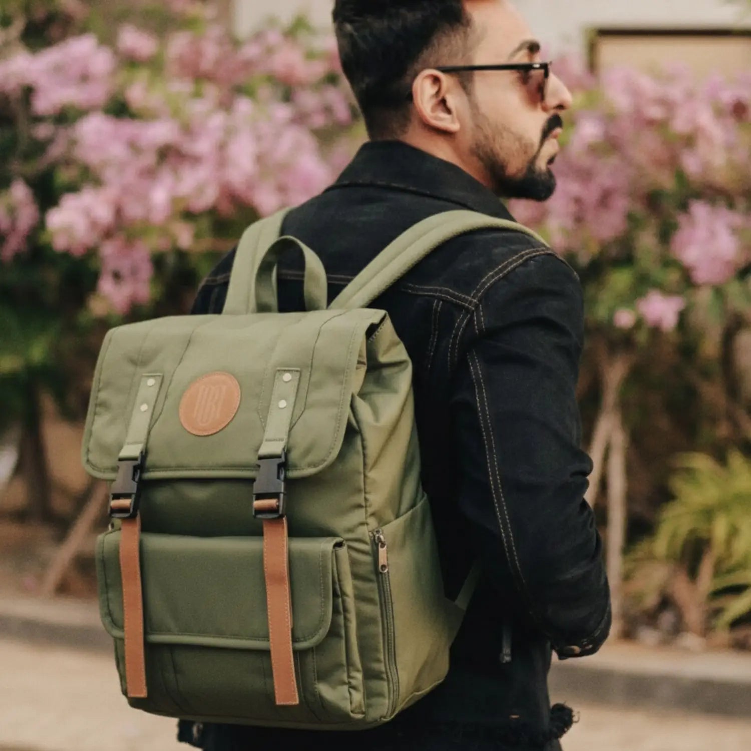 Man wearing a green backpack with a blurred floral background